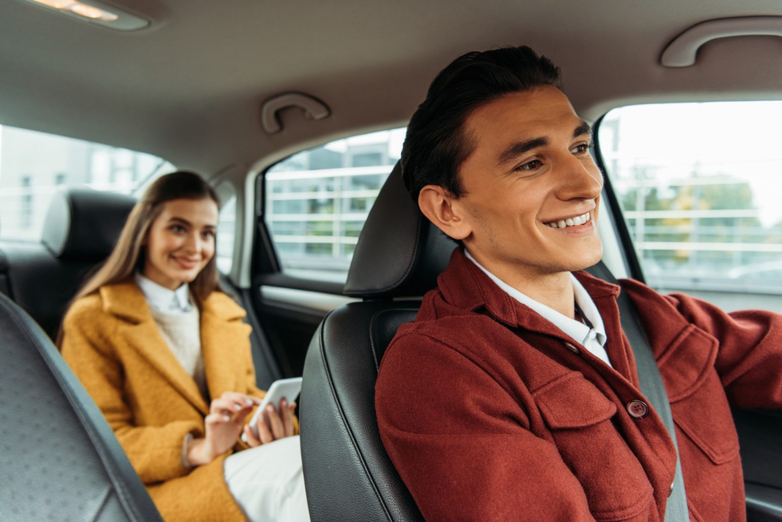 selective-focus-of-smiling-taxi-driver-and-woman-with-smartphone-in-car-e1688700427594-1536x1026